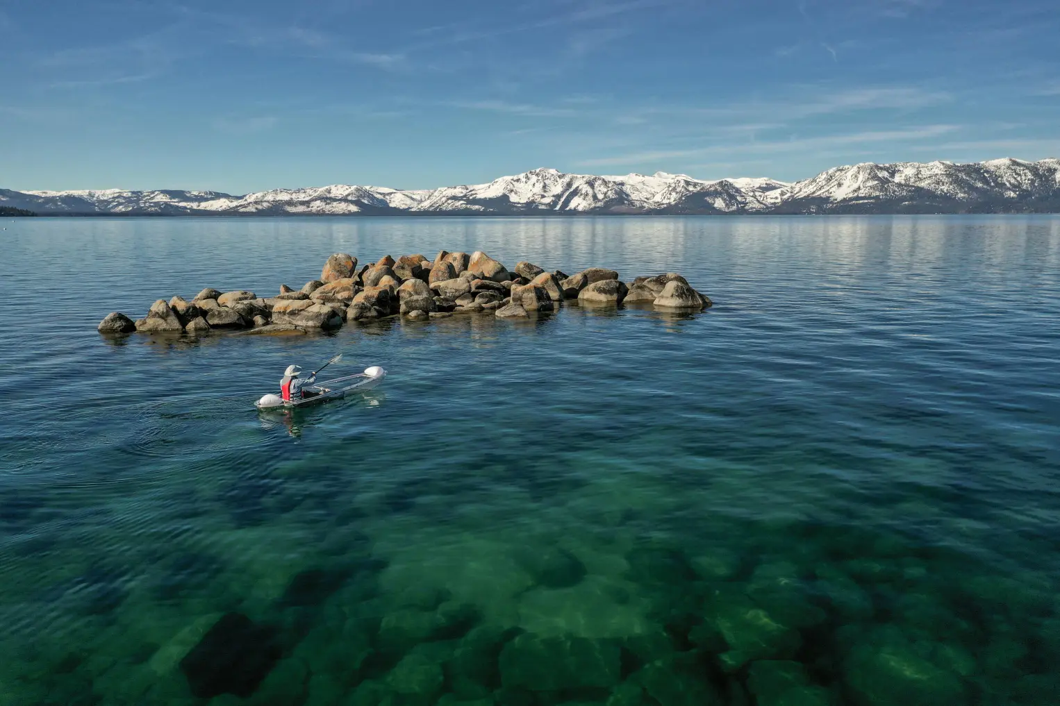 A lone kayaker gliding beside Lake Tahoe's rocky east shoreline