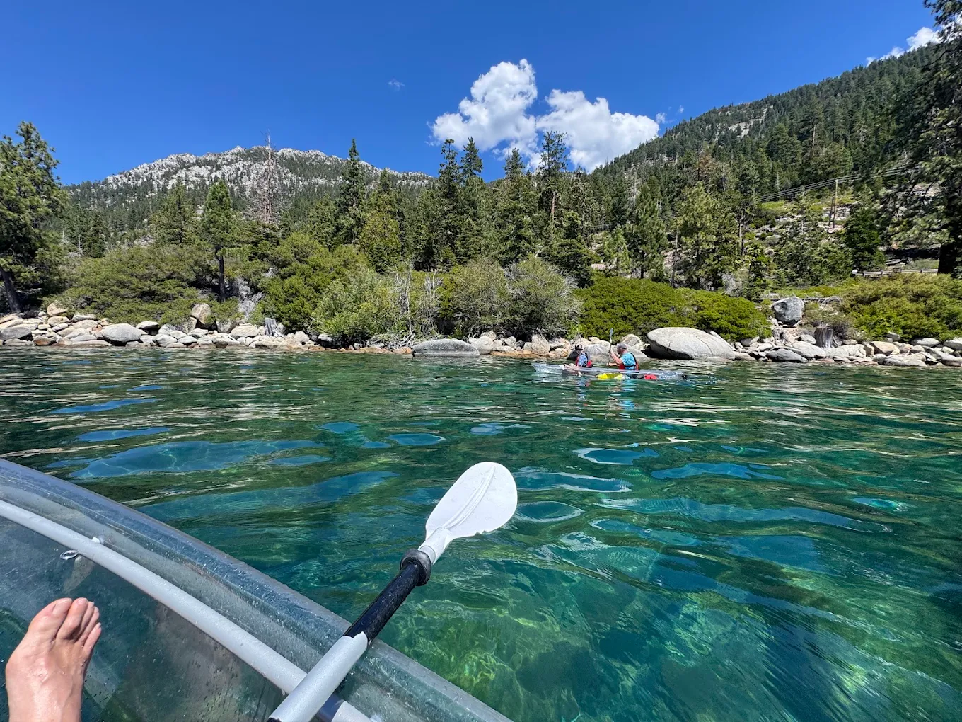 A point-of-view shot paddling a clear kayak across turquoise water