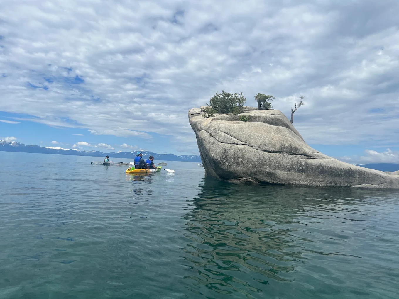 Guests paddling clear kayaks toward the Bonsai Rock formation