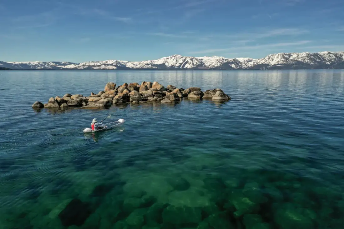 A kayaker gliding beside Lake Tahoe's undeveloped rocky east shoreline