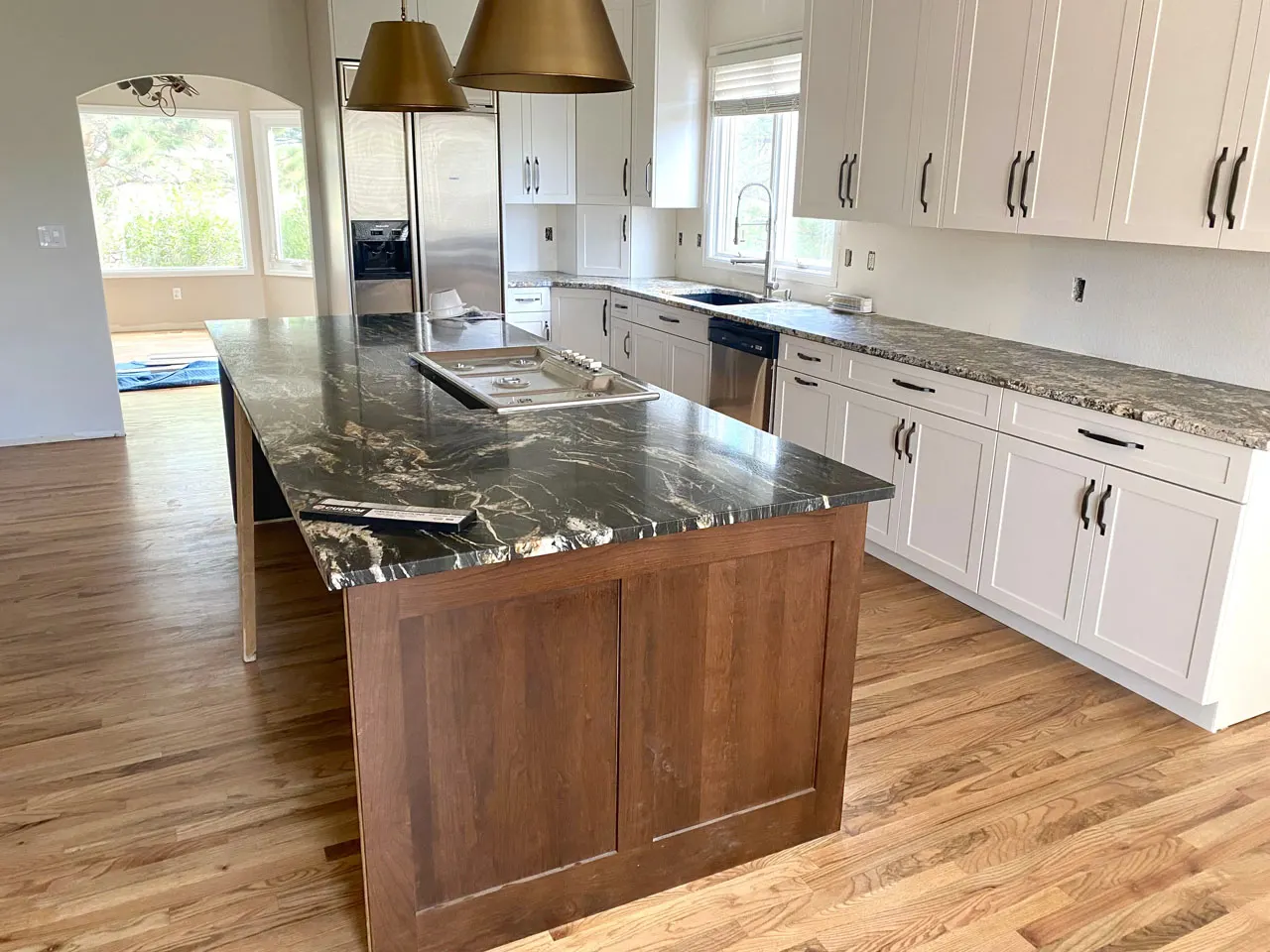 Kitchen remodel with brass pendants and dark wood island
