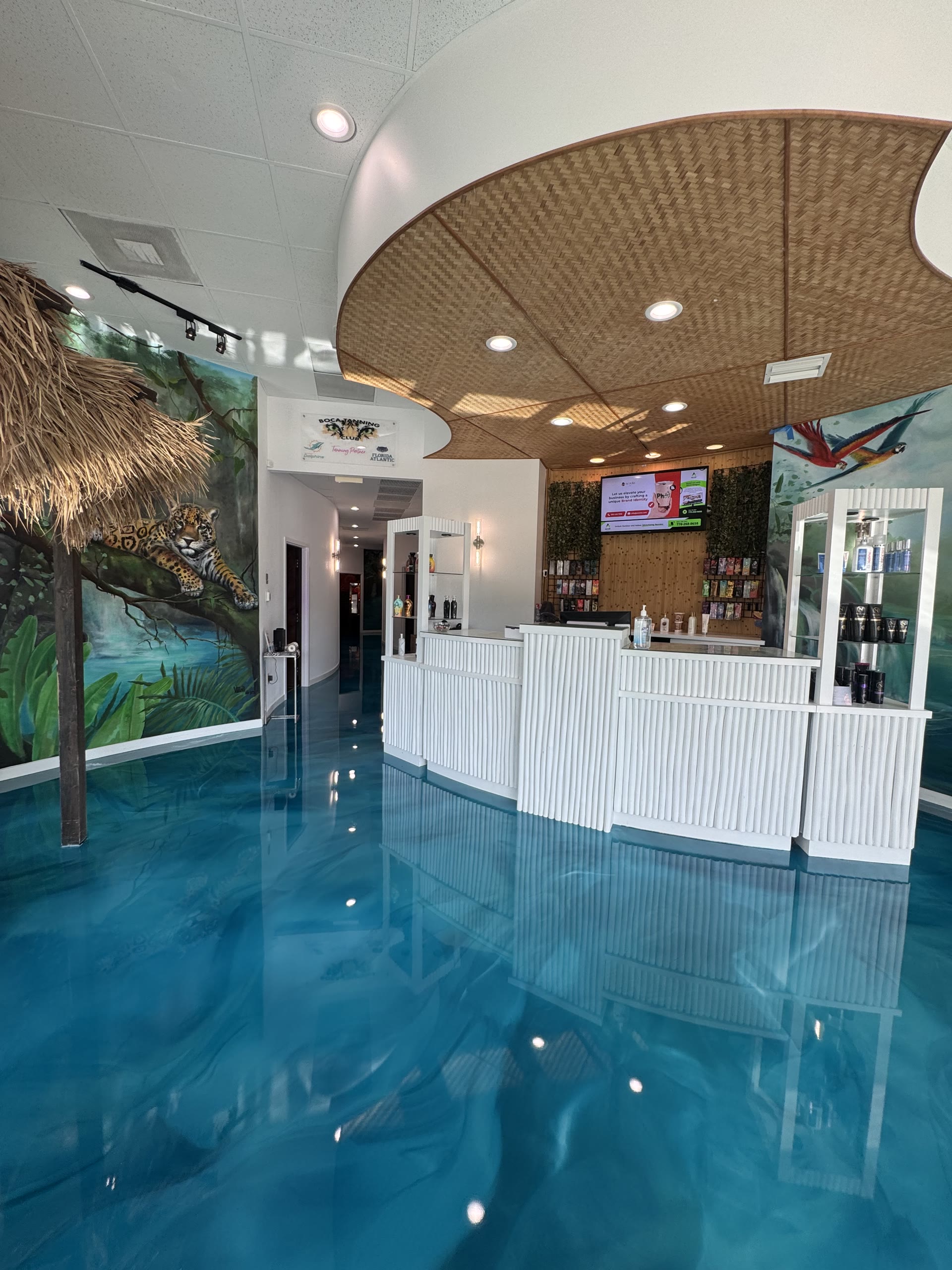 Inside the East Boca location of Boca Tanning Club — reflective jungle-themed lobby and front desk