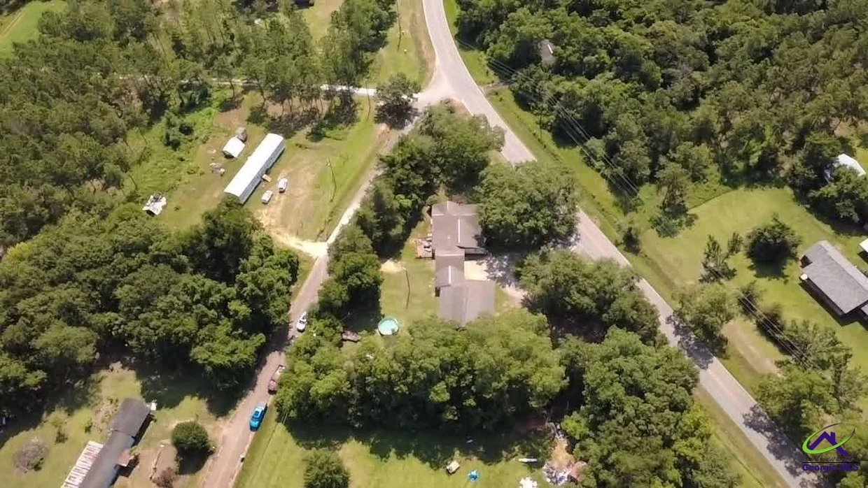 Aerial view of the property surrounded by trees and open land