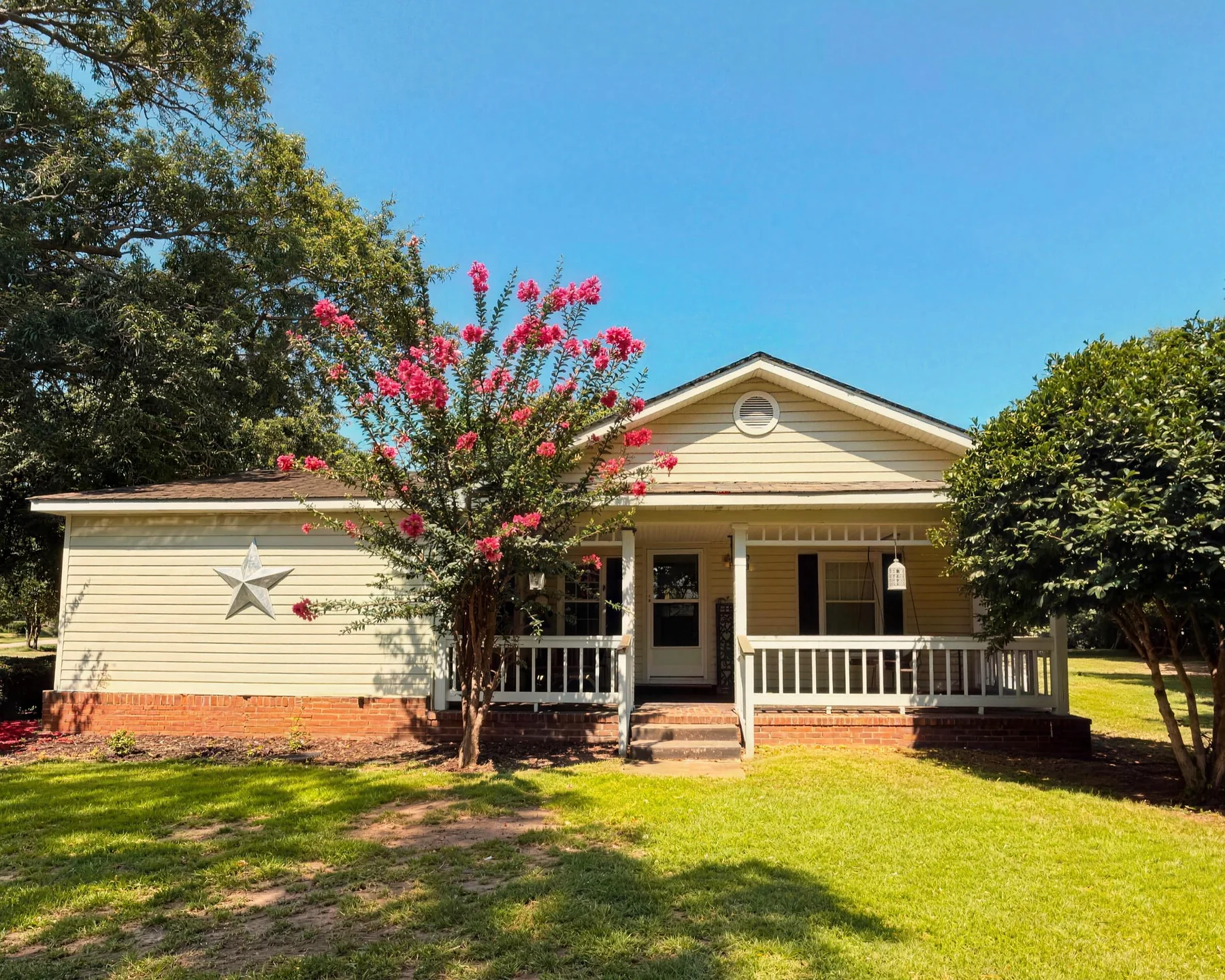 715 Grovania Road: a cream-sided home with a covered front porch, framed by mature shade trees and a blooming crepe myrtle