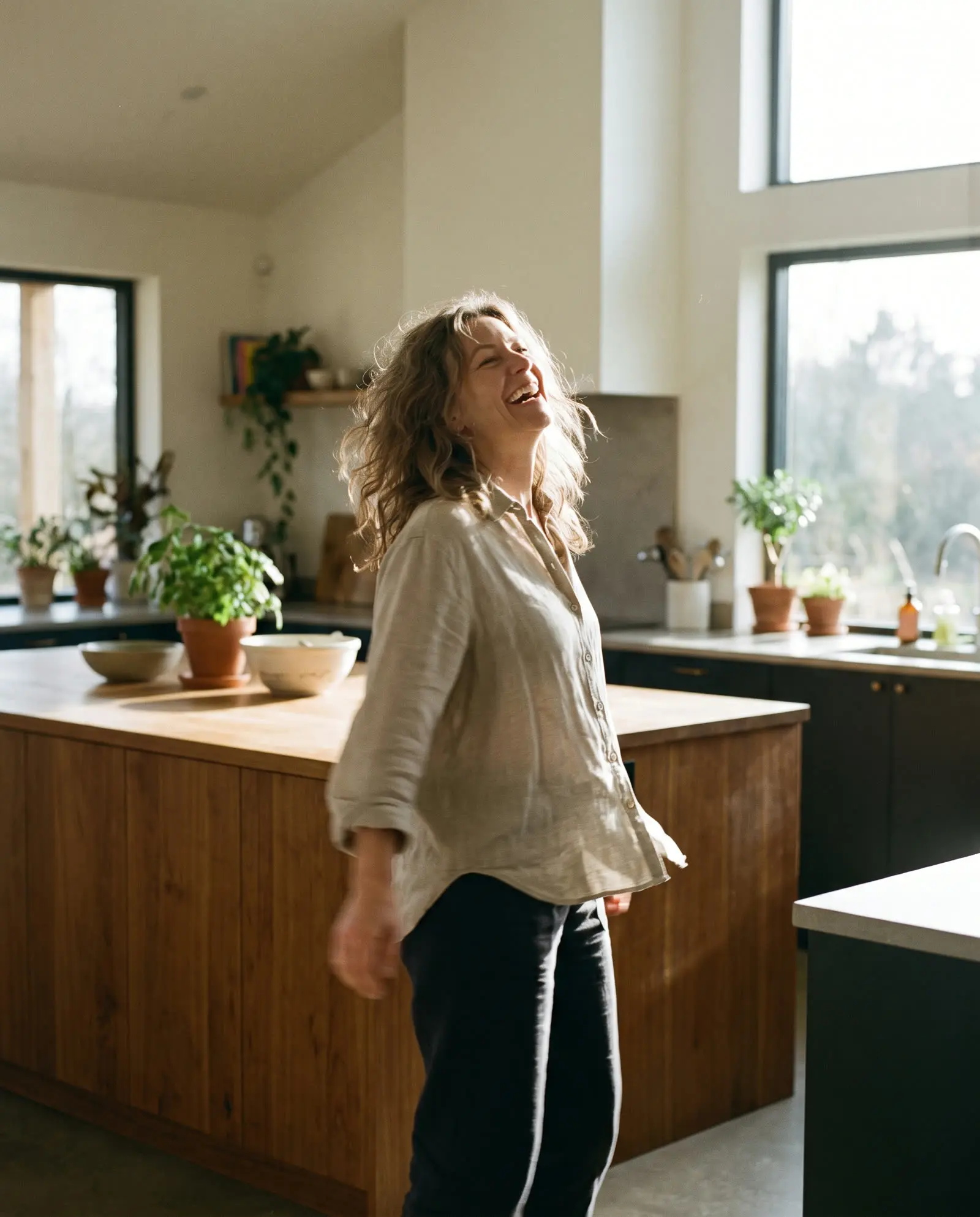 A woman laughing in her sunlit kitchen