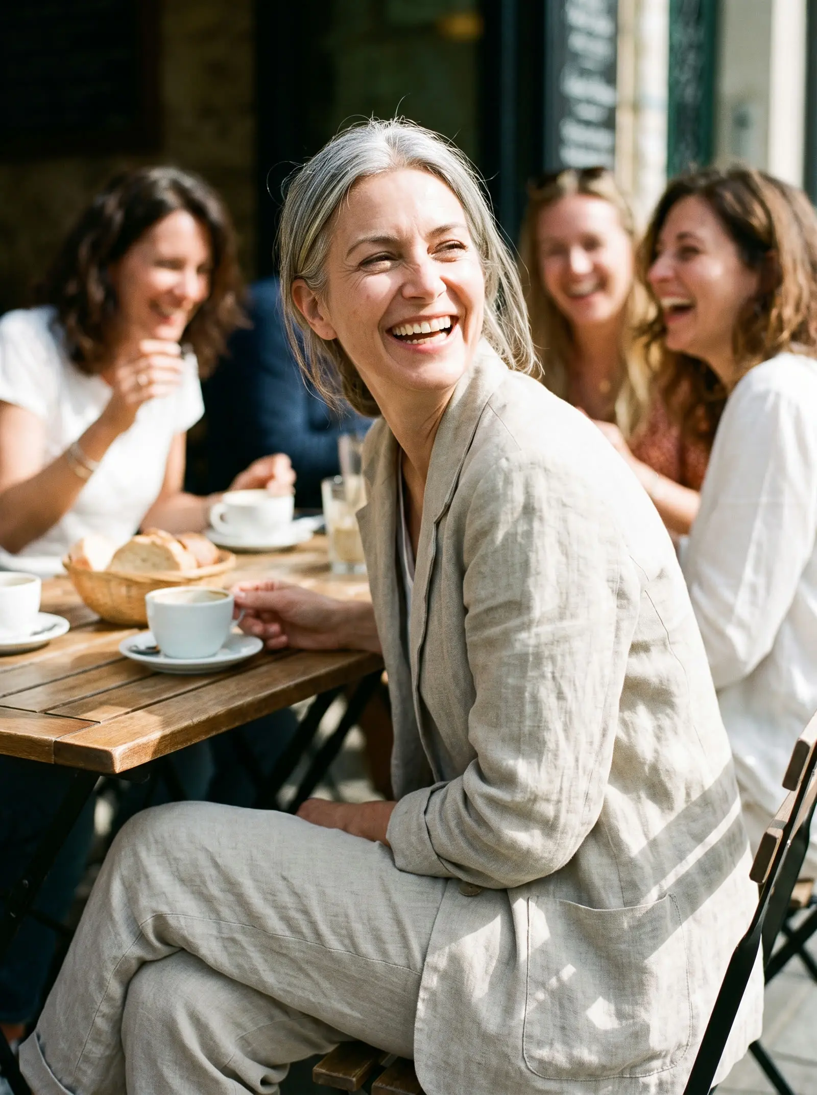 A woman laughing with friends at a cafe
