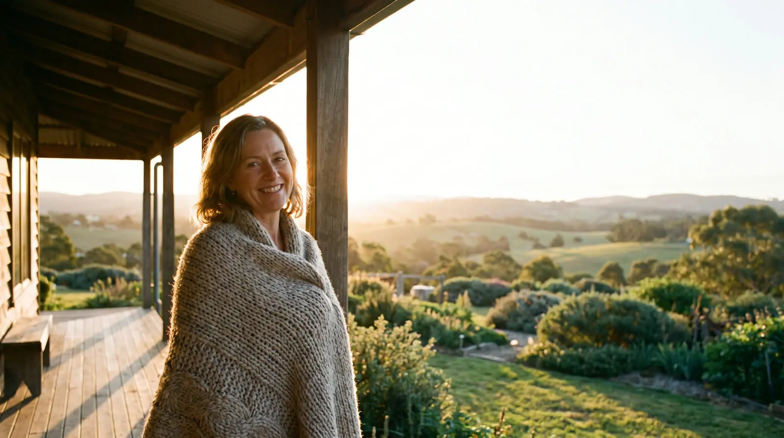 A woman smiling on a porch at sunset