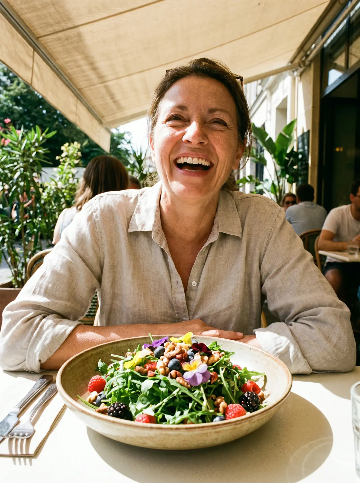 A woman laughing over a colorful salad