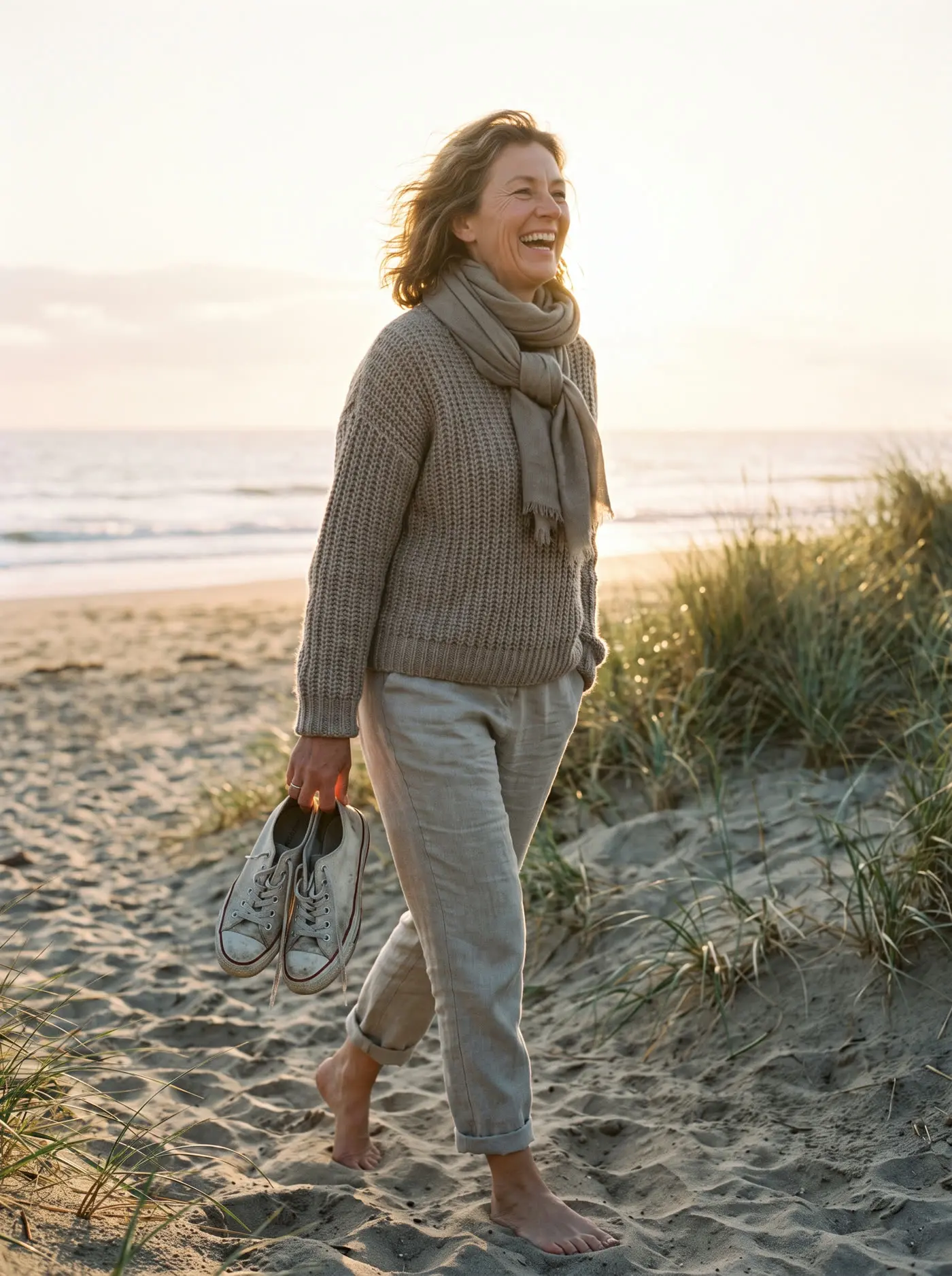 A woman walking on a beach at sunrise