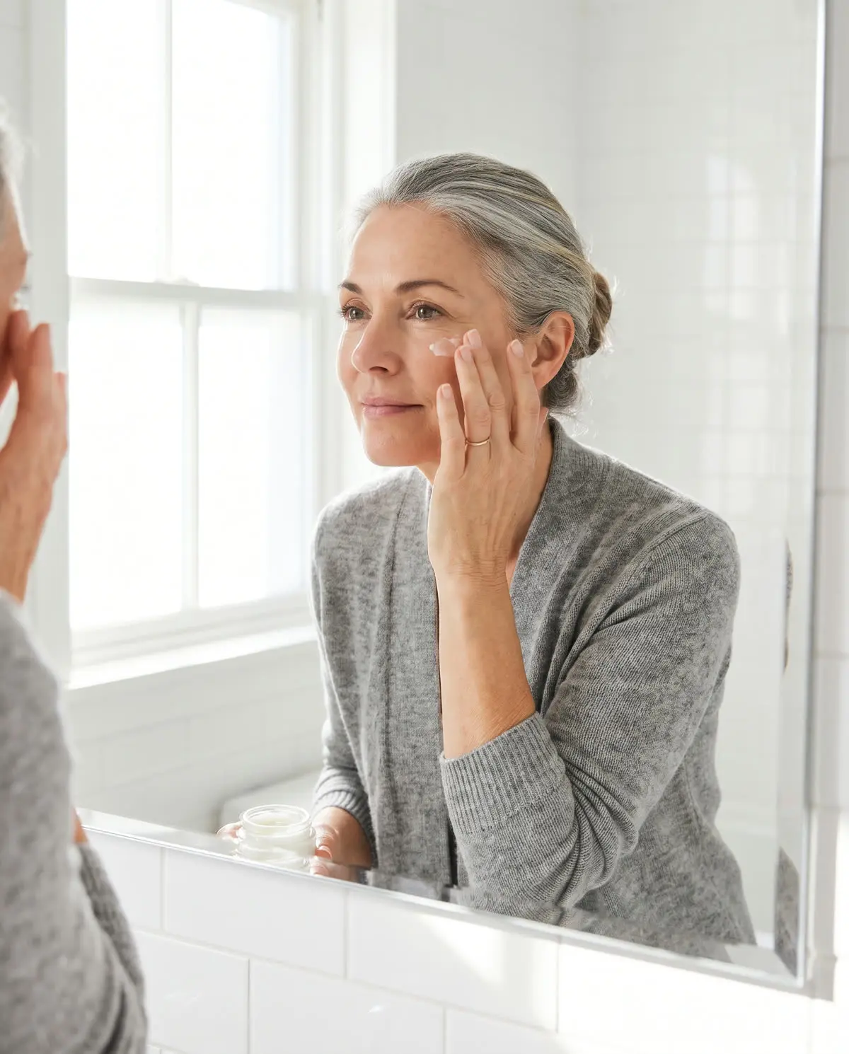 A woman gently dabbing cream near her eye at a mirror