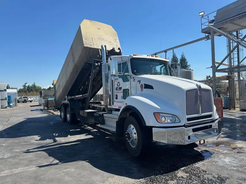 C&W Enterprises roll-off truck lifting a dumpster